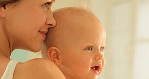 A woman is holding a baby close to her face.