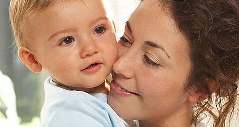 A woman lovingly holds a baby close to her face.