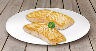 Two cooked salmon fillets with a sprig of parsley on a white plate.