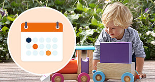 A child plays with a toy train in a garden.
