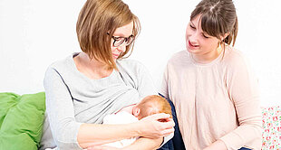 Two women and a baby are depicted in a domestic setting.