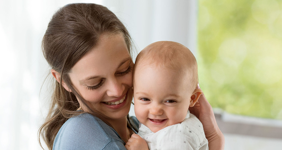 A woman lovingly holds a baby.