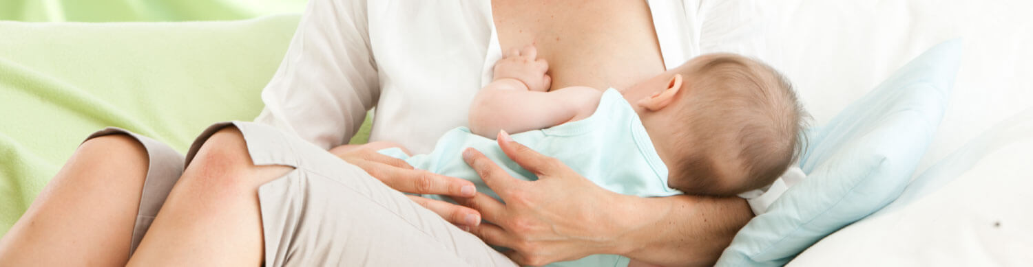 A woman in a white shirt is breastfeeding a baby.