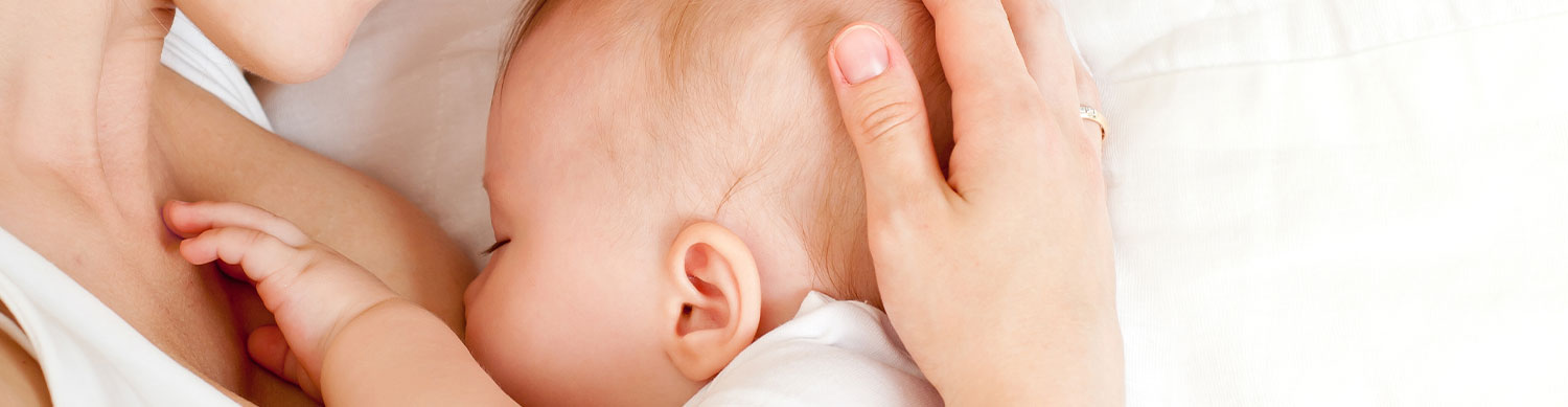A close-up of a mother's hand gently cradling her baby's head.