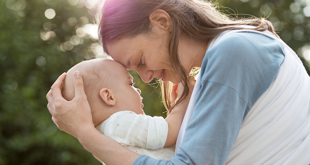 A woman lovingly holds a baby close to her face.