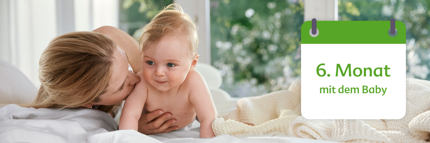 A mother lovingly interacts with her baby, with a calendar indicating the baby is 6 months old.