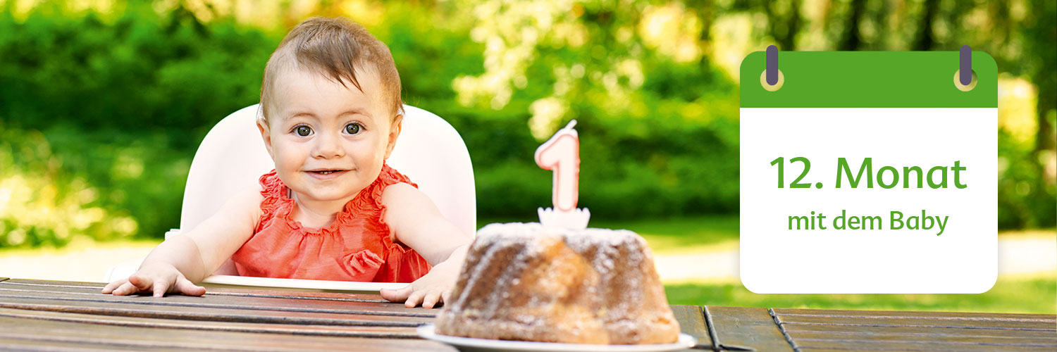 A baby in a high chair with a birthday cake in front of a green garden background.