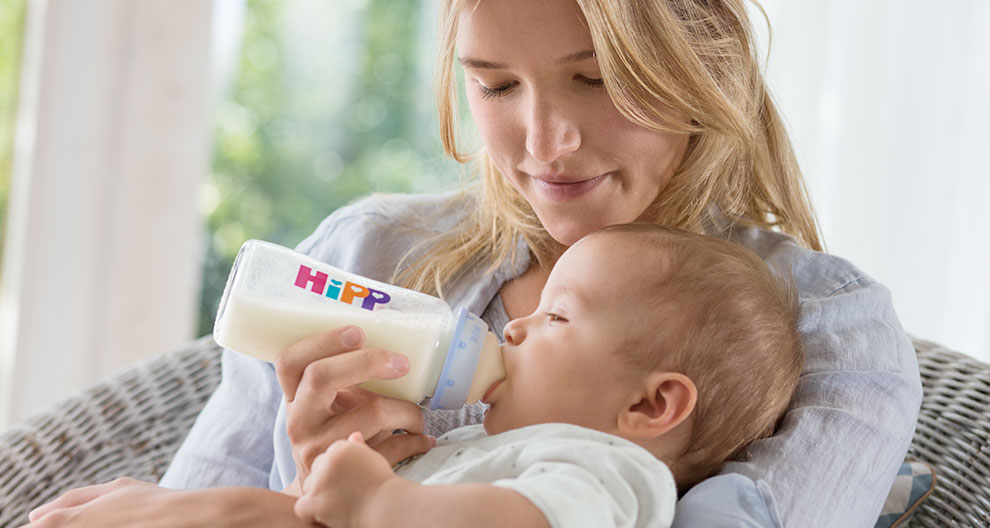 A woman feeds a baby with a Hipp bottle.