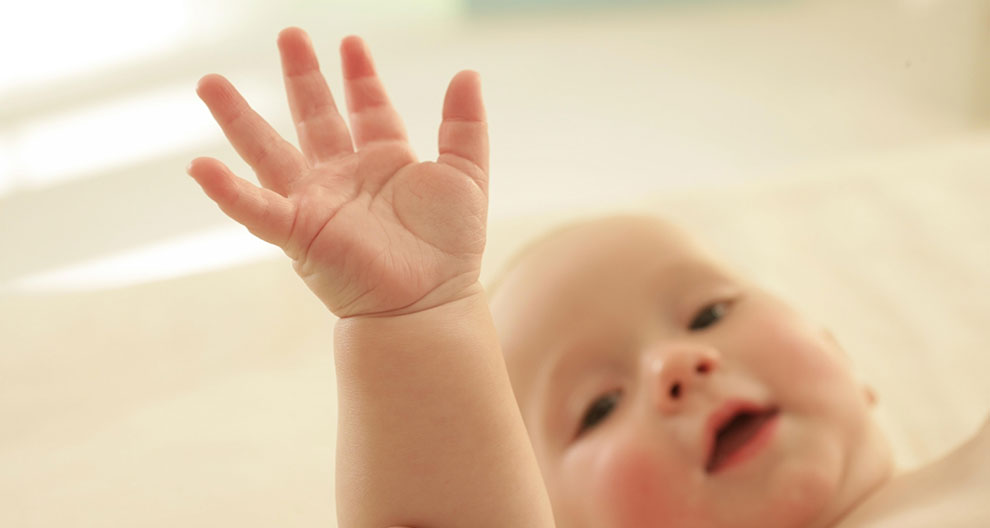 A close-up of a baby's hand reaching out.