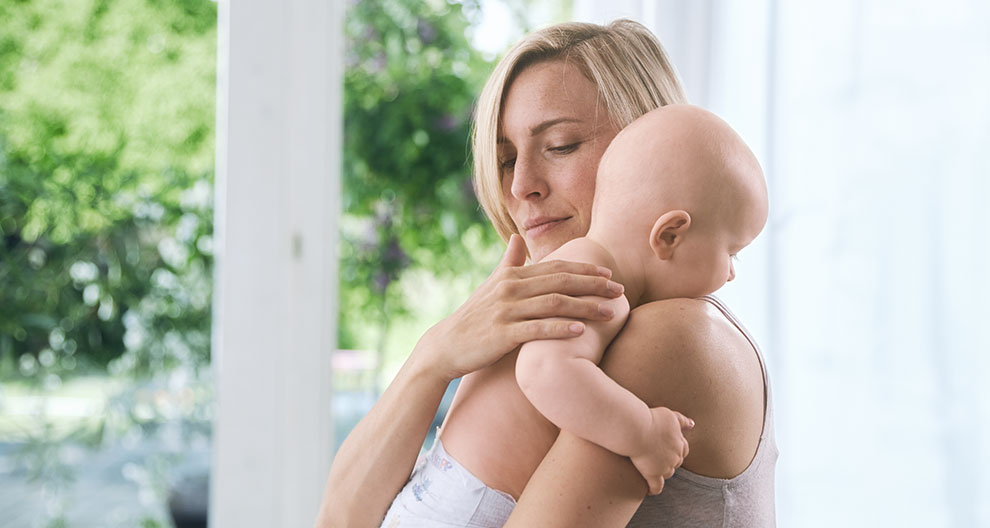 A woman is holding a baby close to her.