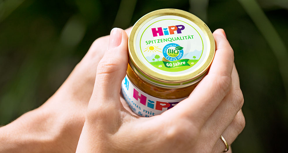 A hand holds a jar with a colorful label, featuring the word "HIpp" and a bio symbol.