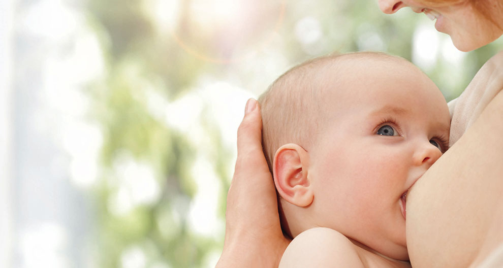 A close-up of a baby's face, with a blurred background, is being cradled by a hand.