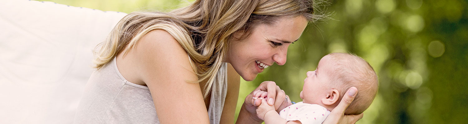 A woman is holding a baby outdoors.