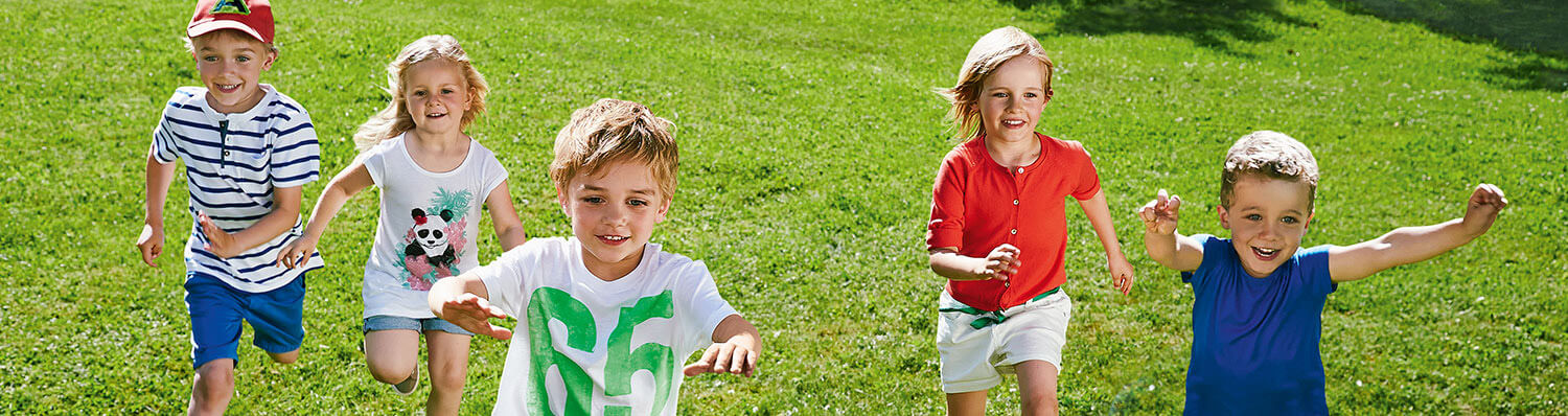 Five children are running on a grassy field.