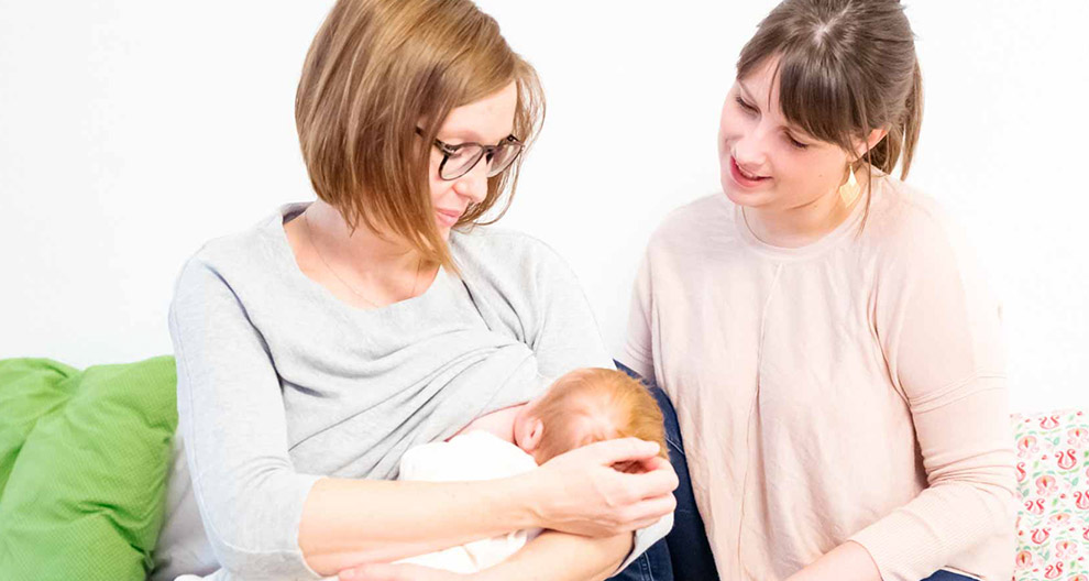 Two women and a baby are depicted in a domestic setting.