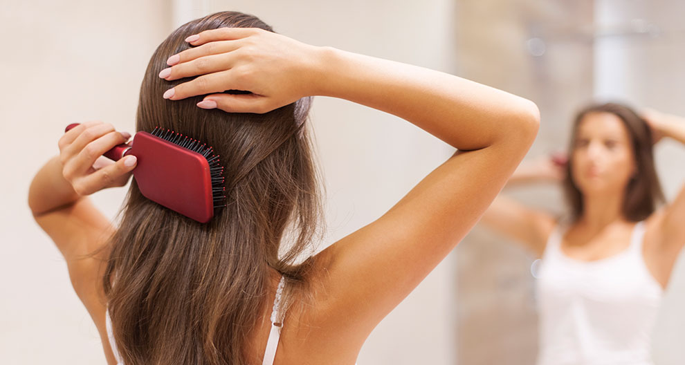 A person is brushing their hair in front of a mirror.