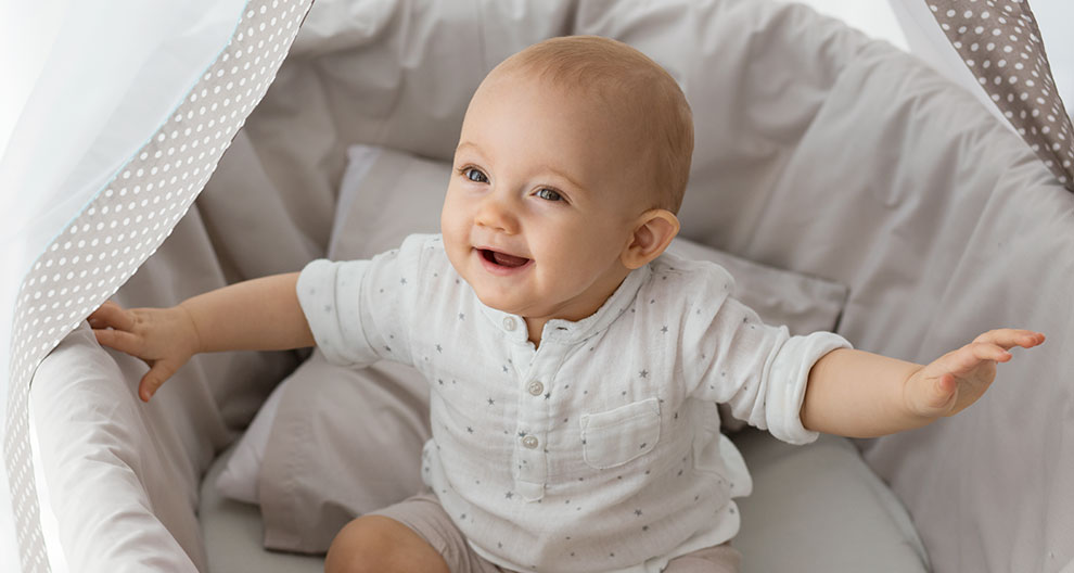 A baby sits in a bassinet.