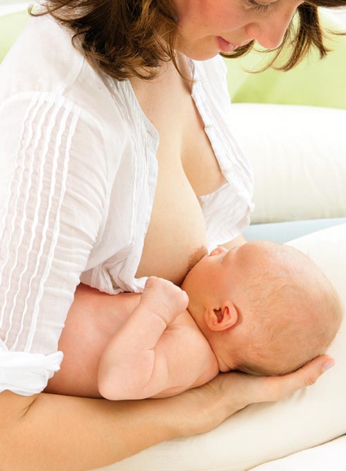 A woman in a white shirt is breastfeeding a baby.