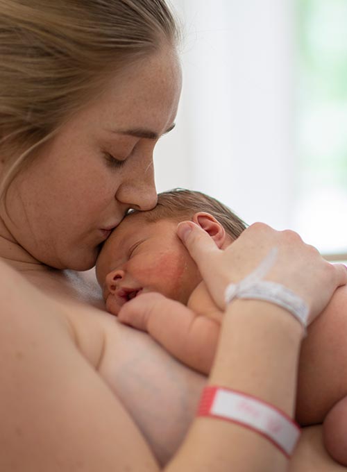 A mother tenderly holds her newborn baby.