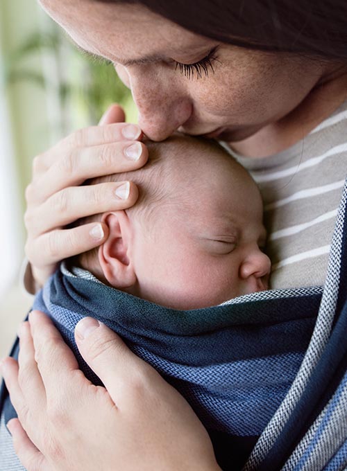 A mother lovingly holds her sleeping baby.