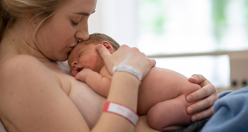 A mother lovingly holds her newborn baby.