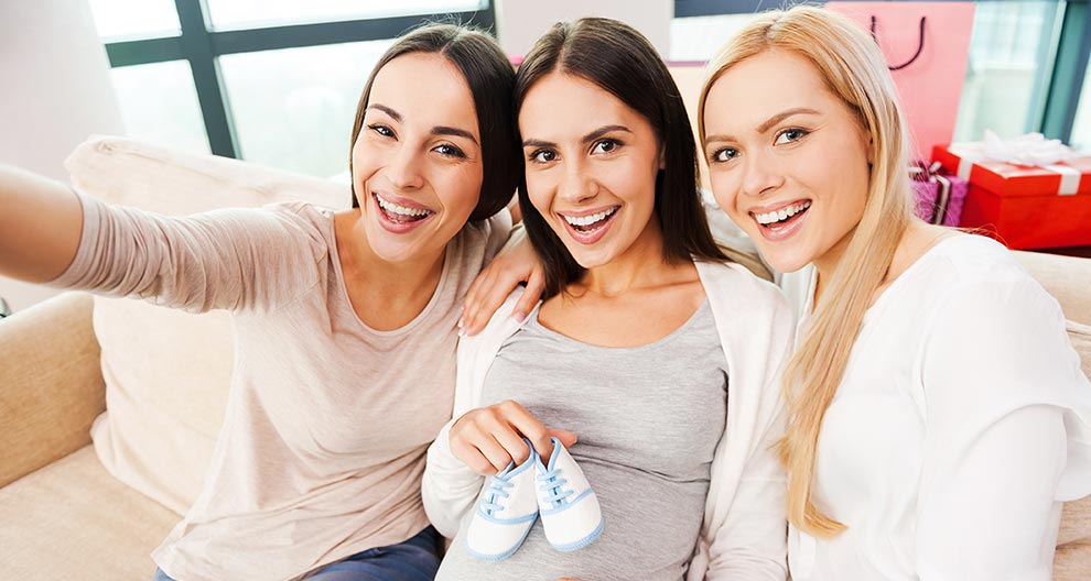 Three women are smiling and posing together.