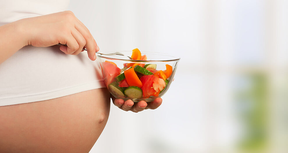 A pregnant woman eating a salad.